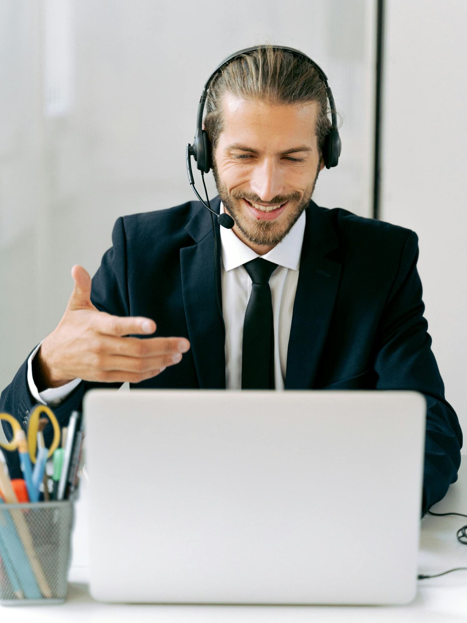 Confident businessman in suit with headset conducting an online meeting from office.
