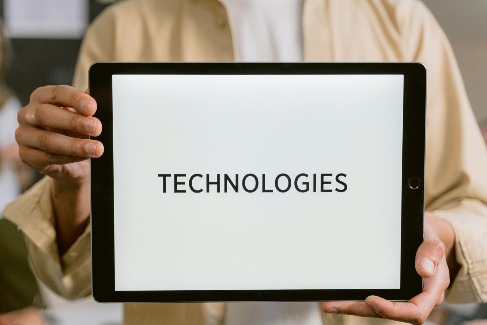 Close-up of a person holding a tablet with the word 'Technologies' on the screen.
